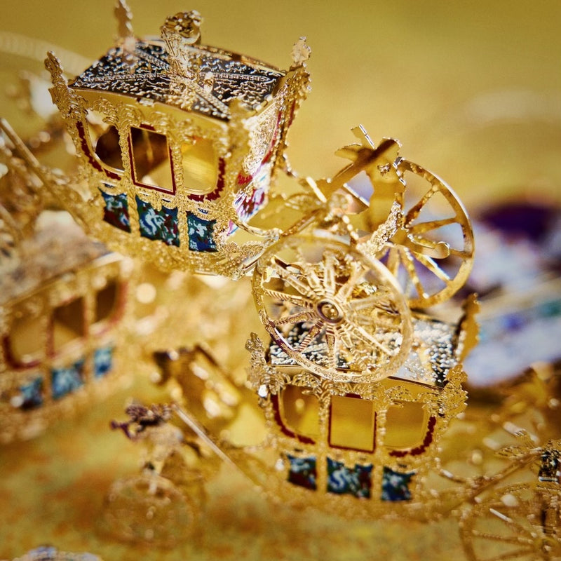 Handcrafted Gold State Coach Christmas Tree Ornament, featuring intricate 24-carat gold details. A stunning royal carriage replica by The London Christmas Company, perfect for adding British elegance to your festive decor. Seen here stacked in a pile of three.